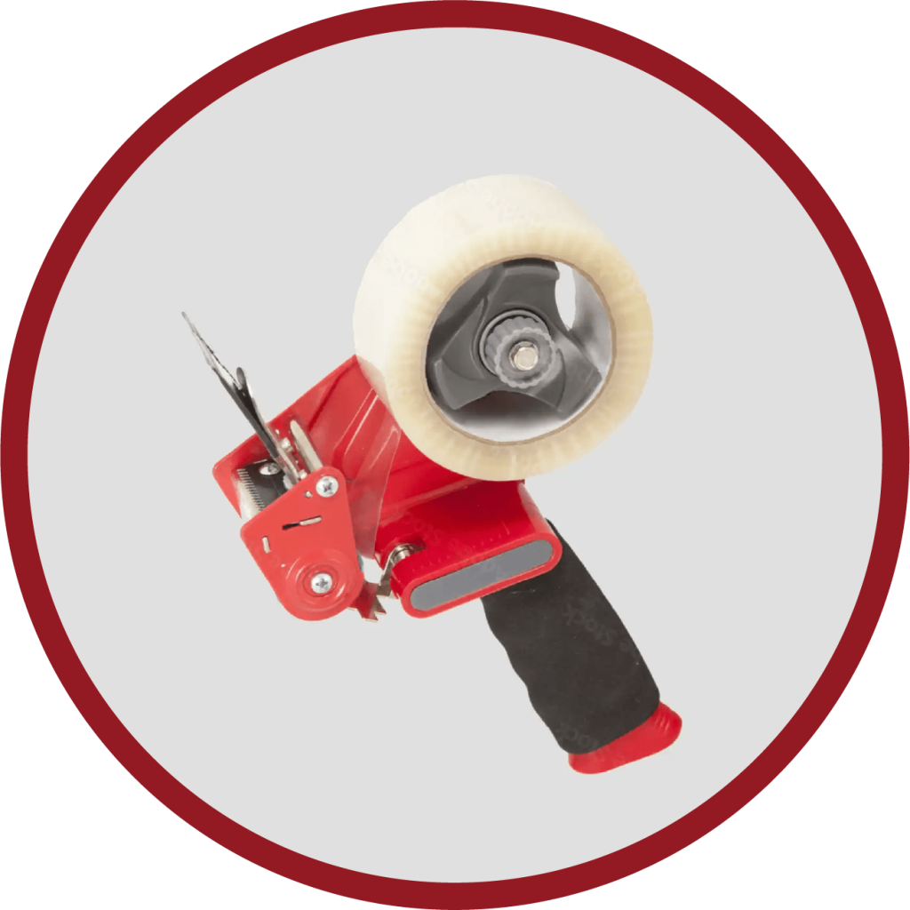A red and black tape dispenser with a roll of clear parcel tape sits elegantly. Its rubberized handle ensures a firm grip, while the dispenser is angled upward. The light gray background accented by a dark red circle border enhances its sleek design.